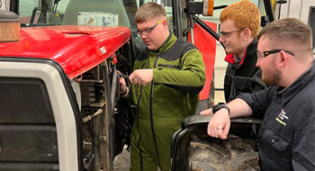 Three agricultural engineering students working on a tractor