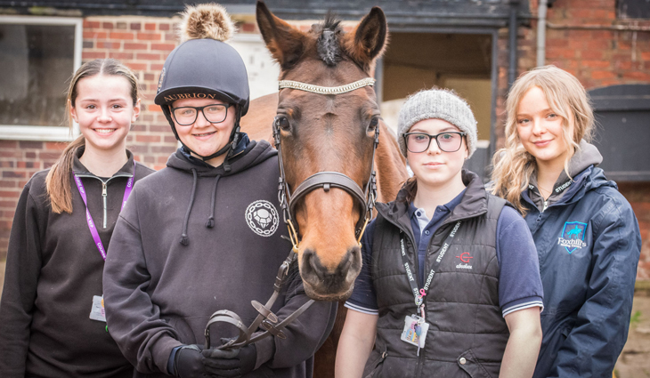 Four Equine students standing either side of a horse