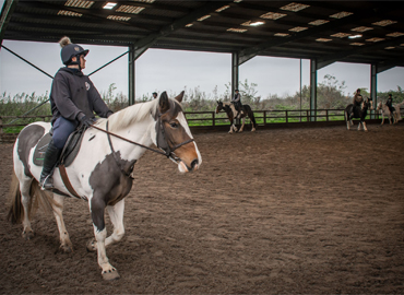 Photo of students riding under the covered arena