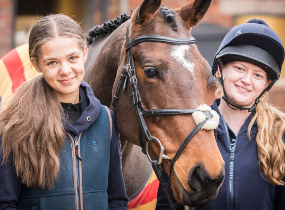 Two Equine students standing either side of a horse