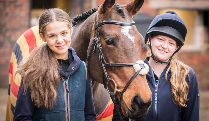 Two Equine students standing either side of a horse