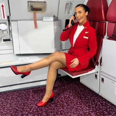 Photo of former Travel and Tourism student Millie Williams sat on an aeroplane on the phone working for Virgin Atlantic