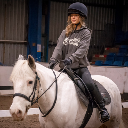 Student riding on horse in indoor arena