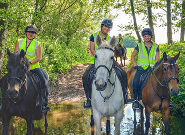 Equine students on horses riding through stream