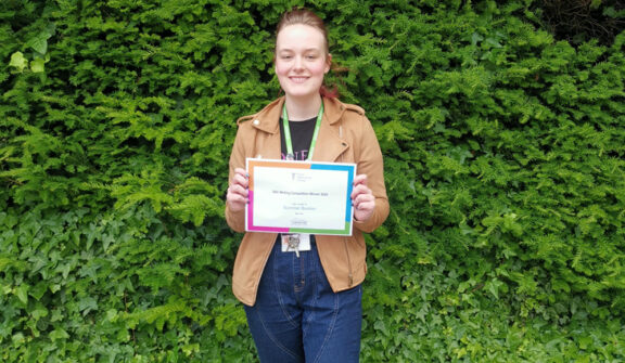 Photo of Summer Buckler holding certificate for winning writing competition