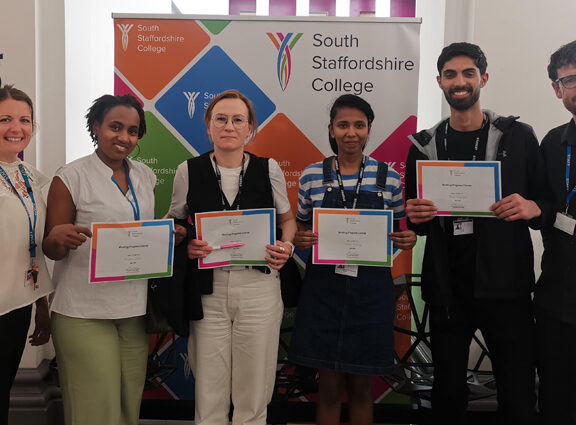 Group of ESOL students holding certificates with staff at Cannock College